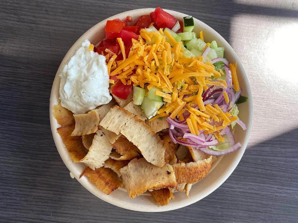 A build-your-own bowl with gyro meat, pita chips, tomato, cucumber, red onion, shredded cheddar and tzatziki