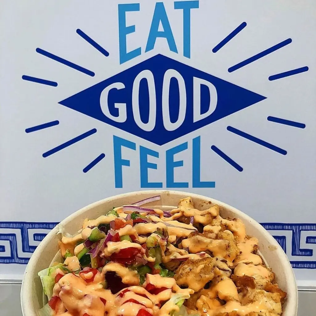 A bowl in front of the 'Eat Good Feel Good' wall inside Pita Bowl